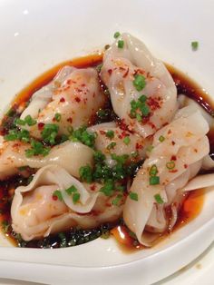 dumplings with sauce and scallops in a white bowl