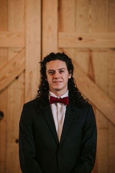 a man in a suit and bow tie posing for a photo with wood doors behind him