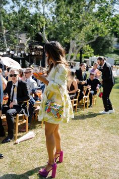 a woman standing in front of a group of people at an outdoor event with umbrellas