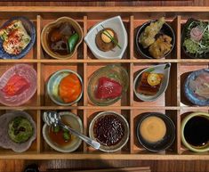 an assortment of sushi dishes are arranged on a wooden tray