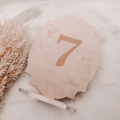 the number seven is next to some dried flowers on a marble table top with a ruler