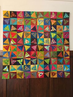 a multicolored quilt hanging on the wall next to a wood panelled door