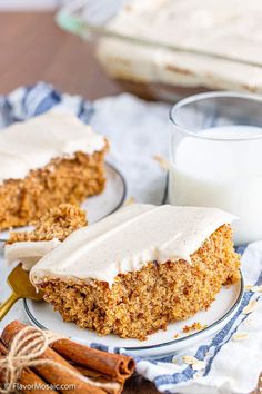 a piece of carrot cake on a plate next to a glass of milk and cinnamon sticks