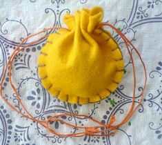 a small yellow bag sitting on top of a table next to some orange string and thread