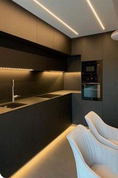 a modern kitchen with black and white furniture in the center, along with lights on the ceiling