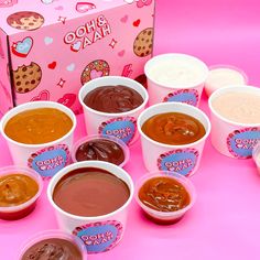 there are many different kinds of ice creams in cups on the pink tablecloth