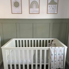 a white crib with two pictures on the wall