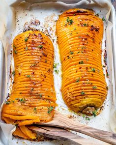 two cooked sweet potatoes in a baking dish with a wooden spoon on the left side