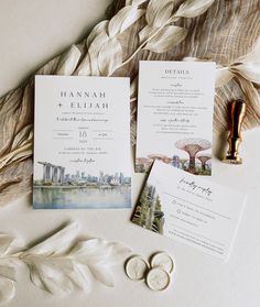 the wedding stationery is laid out on top of some feathers and other things to include