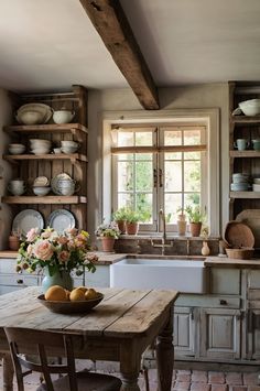 a kitchen with an old wooden table in the center and lots of dishes on the shelves