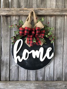 a black and red wreath with the word home hanging on a wooden door hanger