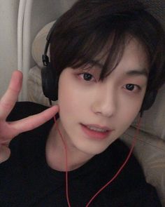 a young man wearing headphones making the peace sign