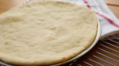 an uncooked pizza crust sitting on top of a cooling rack