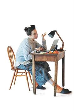 a woman sitting at a desk with a laptop computer and lamp on her lap top