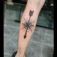 a man's leg with a compass tattoo on it and an arrow in the middle