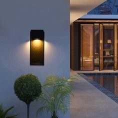 an outdoor wall light next to a swimming pool and patio area with potted plants