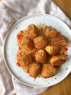 a white plate topped with tater tots covered in sauce on top of a wooden table