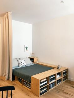 a bed sitting next to a window in a room with wooden floors and white walls