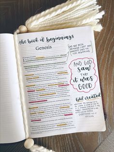 an open book with writing on it sitting on top of a wooden table next to yarn