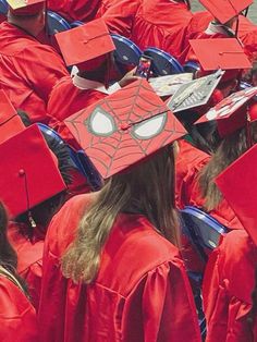 a group of graduates in red caps and gowns with spiderman on their caps