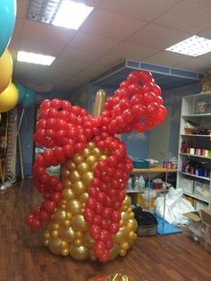 a balloon sculpture in the shape of a bow with gold and red balloons hanging from it