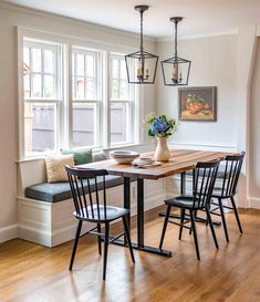 a dining room table with four chairs and a bench in front of the window,