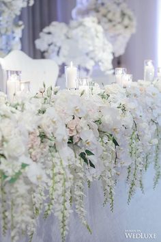 white flowers and candles are lined up on the table