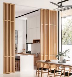 an open kitchen and dining area with wooden partitions on the wall, along with modern furniture