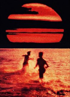 two people are wading in the water at sunset or sunrise, with an orange and black background