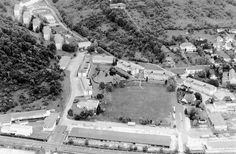 an aerial view of a large building surrounded by lots of trees and buildings in the background