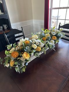 a long table with flowers on it in front of a window