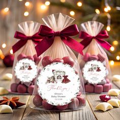 three clear bags filled with chocolates and wrapped in red ribbon on top of a wooden table