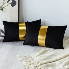 two black and gold pillows sitting on top of a white rug