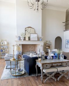 a living room filled with furniture and a chandelier hanging from the ceiling over a fire place