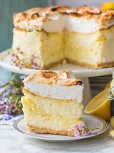 a slice of lemon meringue cake on a plate with the rest of the cake in the background