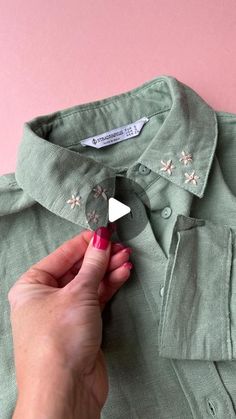 someone is making a button on a green shirt