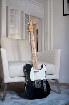 a black and white guitar sitting on top of a chair in a living room next to a couch