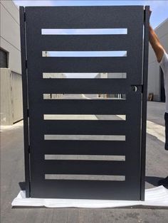 a man standing in front of a large black gate with bars on it's sides