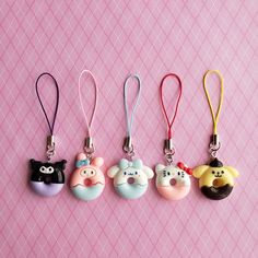 four keychains with cartoon characters on them sitting next to each other in front of a pink background