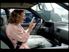 a woman sitting in the driver's seat of a car holding a piece of paper