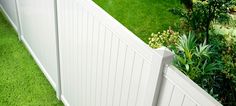 a white fence with green grass in the yard