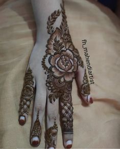 a woman's hand with henna and flowers on the top of her hands