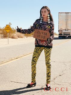 a woman standing in the middle of an empty road holding a sign that says cutta here