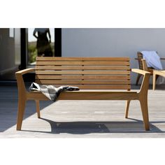 a wooden bench sitting on top of a patio next to two chairs and a blanket