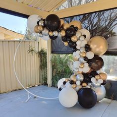 a balloon arch with black, white and gold balloons