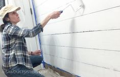 a woman painting the side of a white wall