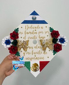 someone is holding up a graduation cap decorated with flowers and butterfly decorations that read, dedicade a la familia por