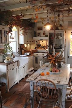 a kitchen filled with lots of white appliances and wooden flooring covered in fall leaves