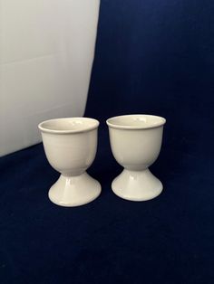 two white bowls sitting next to each other on a blue surface