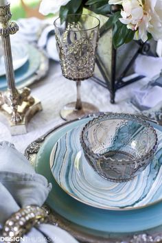 the table is set with blue and white dishes, silver candlesticks, and flowers